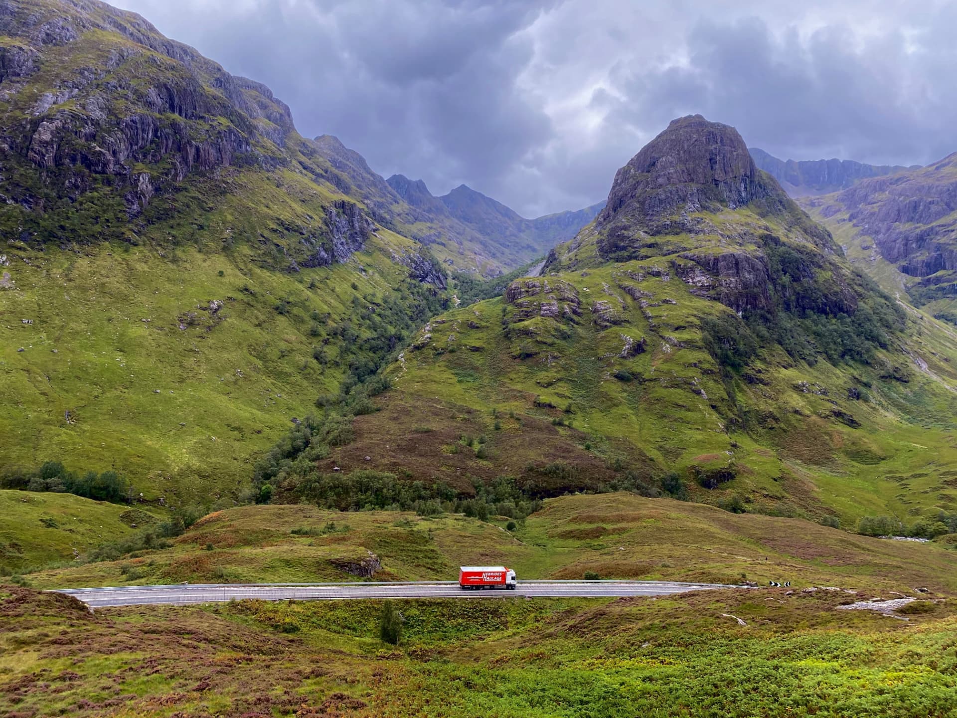 Hebrides Haulage red truck on the A82 through Glencoe with the Three Sisters mountains in the background