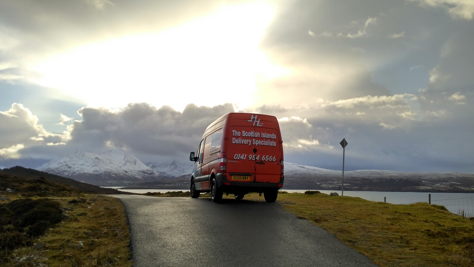 Sprinter van heading toward snow-capped Scottish mountains