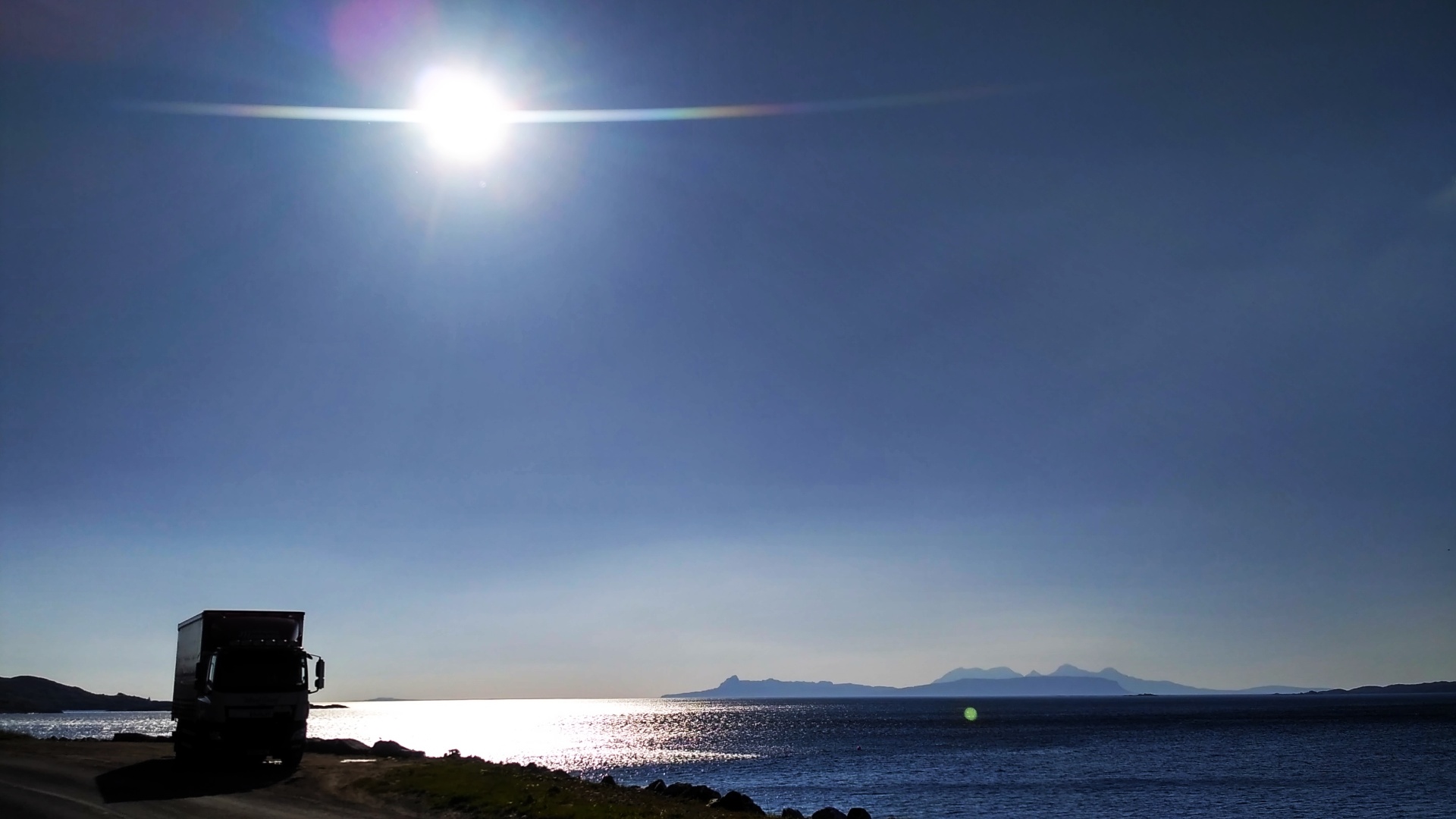 Hebrides Haulage truck on a coastal road at sunset with island views