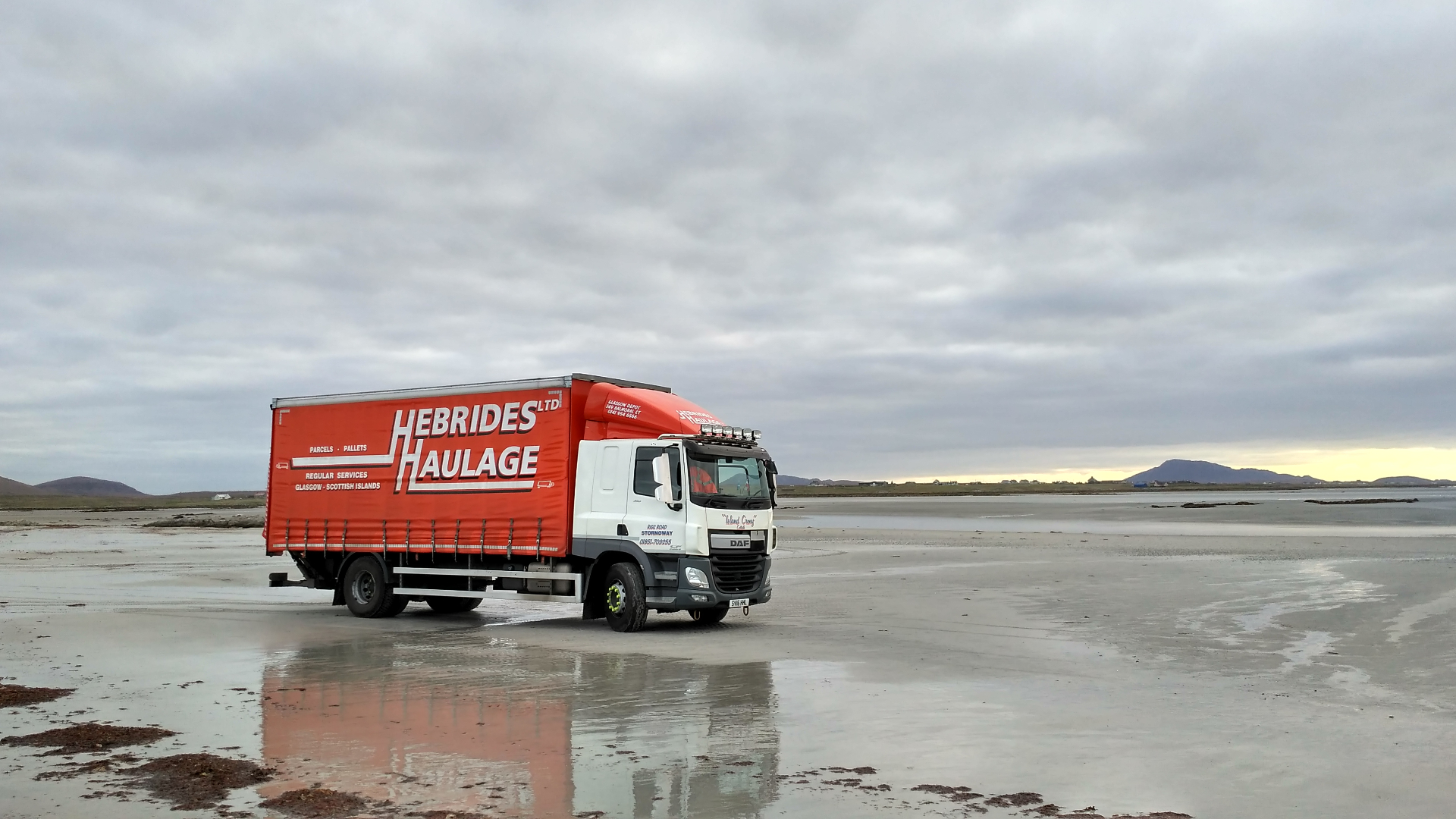 'Island Crony' Hebrides Haulage truck parked on a wet Hebridean beach at low tide